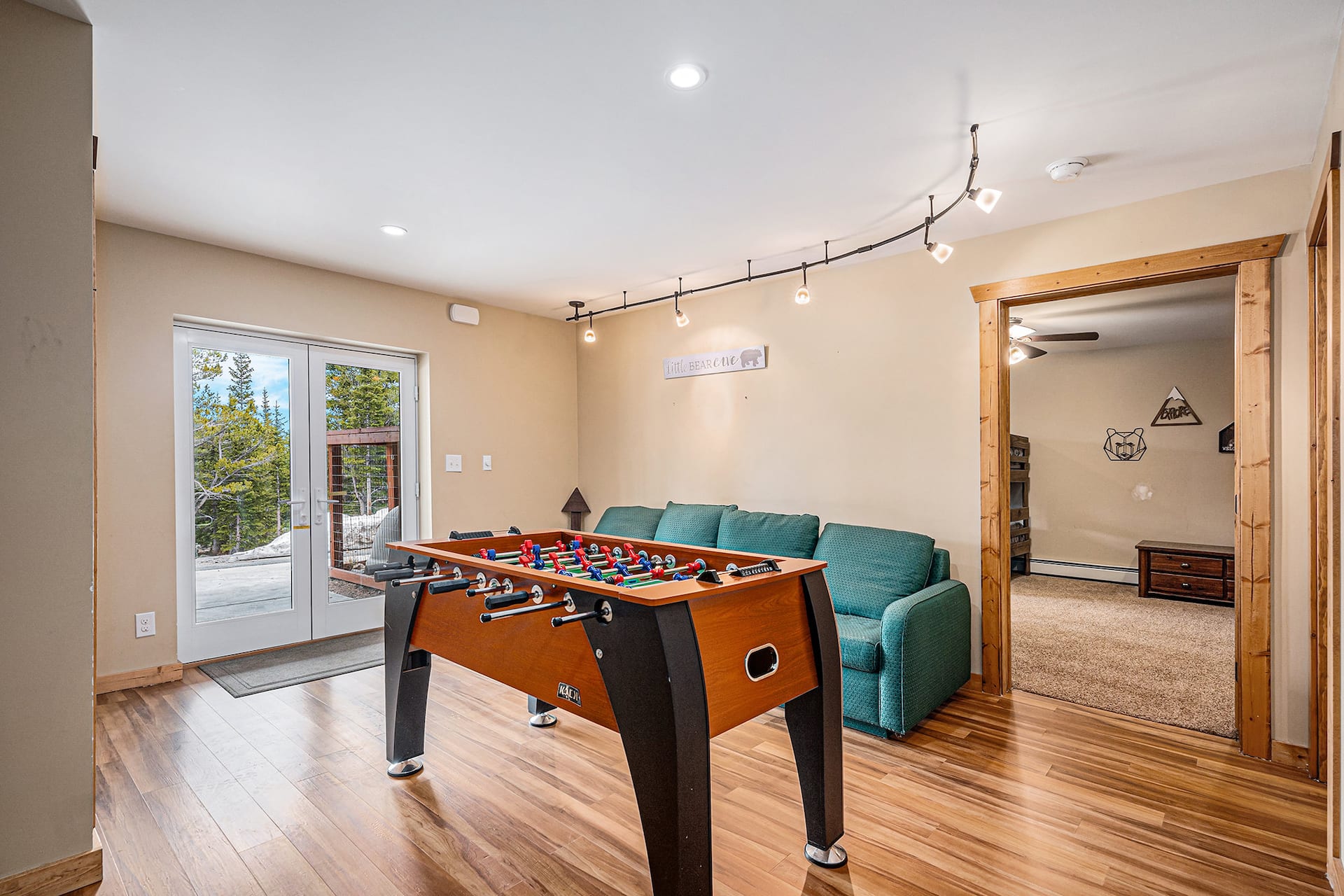 Foosball room with a teal couch and doors out to the deck